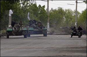 Pro-Russian gunmen atop armored personal carriers passing by barricades on a road leading into Slovyansk, eastern Ukraine, today.