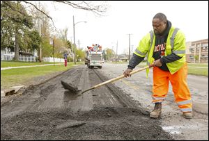 Senior utility worker Shawn Jordan helps remove asphalt as crews work on Detroit Avenue. City crews are fixing as many roads as possible this week.