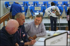 Election officials Alvar Carlson, left, Ed Tucholski, center left, and Jerry Bruns, center right, wait for voters to check in at the Bulldog Center in Rossford.