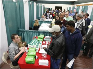 Bryan Preston of Hannaford supermarkets, left, talks with job seekers during a job fair at Columbia-Greene Community College in Hudson, N.Y.