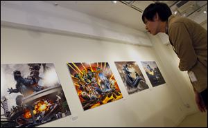 A visitor looks at art work by Yuji Kaida of Godzilla, at Cheepa's Cafe gallery in Tokyo.