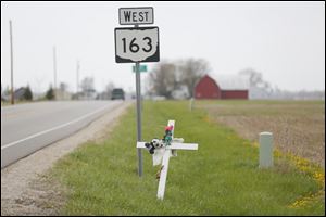 A cross adorned with toy animals and flowers has been placed on State Rt. 163 at Nissen Road in Ottawa County, where Emilee Gagnon, 21, was killed Sept. 23.