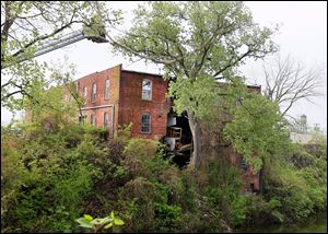 Toledo Fire and Rescue Department personnel examine the rear of a multi-storied building at 20 Broadway, just above Swan Creek, in Toledo.