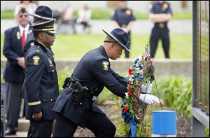 Toledo police Chief William Moton, left, and Officer Thomas Killen present the wreath during a ceremony Monday to honor officers killed in the line of duty. The law enforcement family who gathered in Toledo did so to keep a promise they had made to never forget.