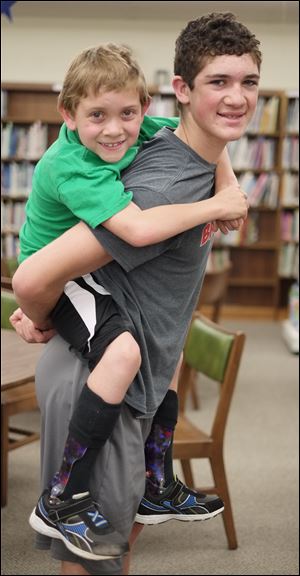 Hunter Gandee, 14, carries his brother Braden Gandee, 7, at Bedford Junior High School. The two will be making a 40-mile walk from Bedford to Ann Arbor over the course of June 7 and 8.
