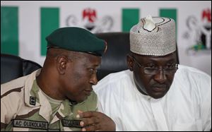 Brig. Gen. Chris Olukolade, Nigeria's top military spokesman, left, talks with Director General, National Orientation Agency, Mike Omeri, during a news conference on the abducted school girls in Abuja, Nigeria, Monday.