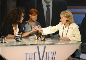 Oprah Winfrey, left, grasps hands with Barbara Walters, right, as co-host Sherri Shepherd looks on during a taping of Walters’ final co-host appearance on ‘The View.’