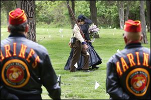 South Toledo resident and Civil War re-enactor Joseph Dowd, 15, center left, escorts his mother, Kathy Dowd, as she places flowers on the graves of veterans Saturday during the seventh annual Veteran’s Memorial Program in South Toledo.  SEE PHOTO GALLERY at toledoblade.com 