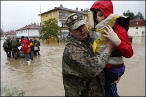A member of the Bosnian army carries a boy rescued from his home, during floods,   in the Bosnian town of Maglaj, 150 kms north of Sarajevo.