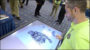 Michael Fieldson, the civilian project manager for the Tactical Assault Light Operator Suit at McDill Air Force Base, looks at sketches of the body armor exoskeleton during the Special Operations Forces Industry Conference in Tampa, Fla.