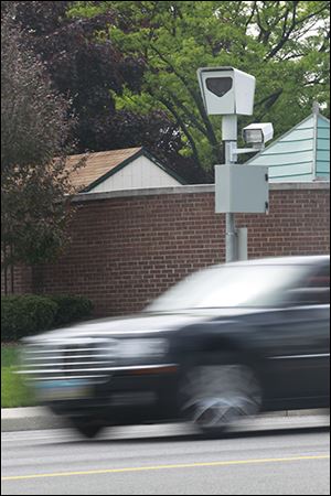 A vehicle passes a red-light speed camera near the intersection of Cherry Street and East Delaware Avenue in Toledo.