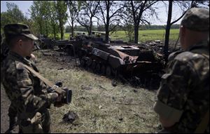 Ukrainian soldiers look at charred APCs at a gunfight site near the village of Blahodatne, eastern Ukraine today.