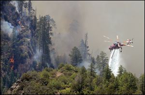 A firefighting helicopter drops water on a forest fire in Oak Creak Canyon in Sedona, Ariz., Thursday. The human-caused Slide Fire started Tuesday and had burned 7 1/2 square miles in and around Oak Creek Canyon, a scenic recreation area along a highway between Sedona and Flagstaff that normally would be teeming with tourists as the Memorial Day weekend approaches.