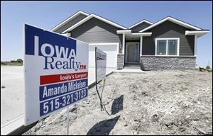 A sign sits in front of a new home for sale in West Des Moines, Iowa. 