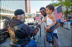 Commander Kendall ‘Doc ’ Roth, left, of the American Legion Riders of Fulton County,shakes hands with Robert Payton, Jr., 3, and his father, Robert, of Florida.