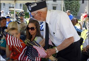 Roy Barnes, right, hands-out flags to Braden Keel, left, 5, from Toledo and Saydee Perry, 15, center, from Toledo.