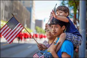 of Isaiah Pullella, 15, and his brother Tyler Pullella, 4, of Toledo wave  flags and wait as the next round of parade participants makes its way down the street.