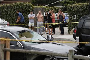 People look at a black BMW sedan driven by a drive-by shooter today in Isla Vista, Calif.
