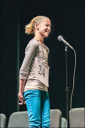 Phoebe Jackson of Woodmore Elementary, here standing perfectly still, is declared the champ of The Blade Northwest Ohio Champion-ship Spelling Bee at Owens Community College in March. Sometimes, she says, she spins while practicing. 