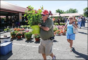 Pete Kaighin of Perrysburg carries a rose bush that he and his wife, Analie, right, bought Sunday at the Flower Day weekend event.