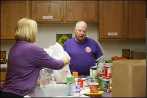 Laura Guitteau (cq), left, pack can goods, fruit and vegetables, for a Nightingales Harvest client delivery while Keith McCall, board president, right, helps on April 1, 2014. Nightingales Harvest is a food pantry specifically for cancer patients.