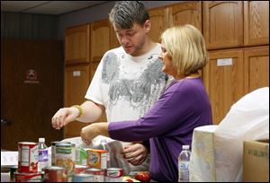 Daren Featherston and Laura Guitteau, right, pack can goods, fruit and vegetables, for a Nightingales Harvest client delivery.