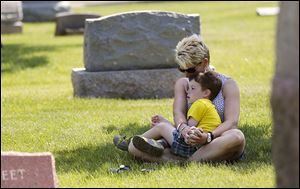 Patricia Gaffney, with her son, Alexander, 4, of Perrysburg bows her head in prayer at the Fort Meigs Union Cemetery service.