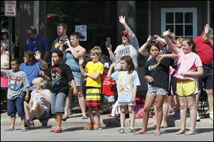 Children along the parade route in Sylvania wave as the marchers pass.     Hundreds of people crowd both sides of Main Street from the bridge over Ten Mile Creek to Erie Street for the parade. It was followed by a service at Veterans Memorial Field. Before the parade, the city hosted a ceremony at Toledo Memorial Park.