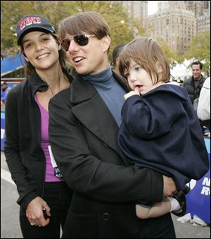 Actress Katie Holmes, husband Tom Cruise, center, and their daughter Suri pose for a photograph after Holmes finished running the New York City Marathon in November, 2007.
