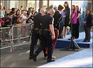 A fan is walked off carpet in handcuffs after allegedly attacking Brad Pitt at the world premiere of 