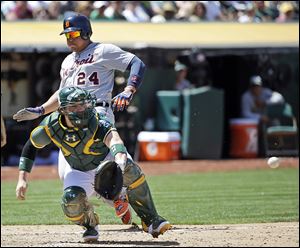 The Tigers' Miguel Cabrera scores past Oakland’s Derek Norris on a double by Victor Martinez in the seventh inning.