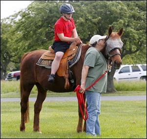 Ty Carroll, 14, of Rossford takes a ride on a horse called Big Red, who is guided by volunteer Joan Miller.