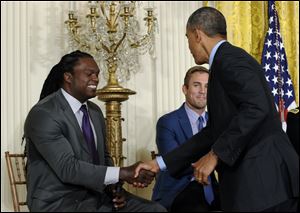 President Barack Obama shakes hands with former football player Lavar Arrington, left, as former professional soccer player and current ESPN analyst Taylor Twellman watches at center, after Obama spoke at the White House Healthy Kids & Safe Sports Concussion Summit today in the East Room of the White House in Washington.