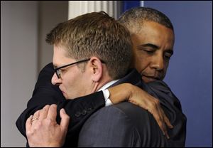 President Barack Obama gives White House press secretary Jay Carney a hug after announcing that Carney will step down later next month, during a surprise visit to the Brady Press Briefing Room today at the White House.