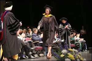 ABOVE: Tracy Tran crosses the stage after being hooded in recognition of her master of science in biomedical sciences during the 43rd commencement of the University of Toledo college of medicine and life sciences on Friday.