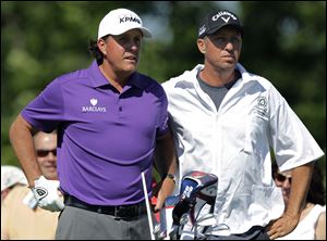 Phil Mickelson, left, talk with his caddie Jim MacKay before teeing off on the first hole today in Dublin, Ohio.  Mickelson says he's co-operating in an insider trading investigation involving him, investor Carl Icahn and Las Vegas gambler Billy Walters but maintains he did nothing wrong. 