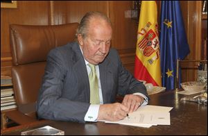 In this photo released by the Royal Palace today,  Spain's King Juan Carlos signs a document in the Zarzuela Palace opening the way for his abdication.