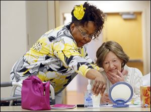 Volunteer cosmetologist Brenda Holsey, left, helps Liza Lacy of Toledo with her new makeup during a ‘Look Good, Feel Better’ event at Mercy St. Anne Hospital on Monday.