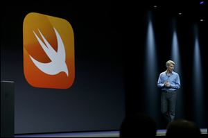 Apple senior vice president of Software Engineering Craig Federighi walks next to a symbol for Swift, a new programming language, while speaking at the Apple Worldwide Developers Conference today in San Francisco.