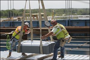 Ironworkers from Local 25 Charlie Bunker, left, and Jason Harris direct a load of stay in place forms onto the work surface. 