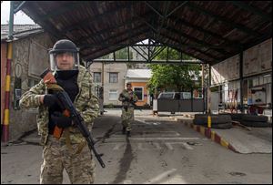 Pro-Russian armed men walk in an entrance to a border guards base, which they seized, on the outskirts of Luhansk, Ukraine, today.