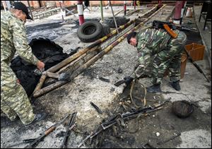 Pro-Russian armed men examine destroyed rifles at a border guards base, which they seized, on the outskirts of Luhansk.