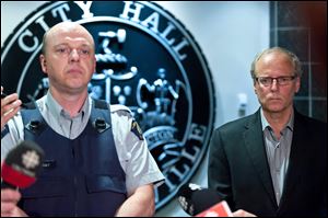 Royal Canadian Mounted Police officer Damien Theriault and Mayor George LeBlanc pause to collect themselves before addressing the media during a late night news conference at City Hall in Moncton,  New Brunswick  Wednesday.