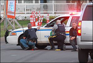 Police officers take cover behind their vehicles in Moncton, New Brunswick, on Wednesday.searching for a suspect. 
