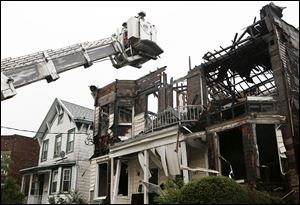 A firefighter uses a ladder to examine the damaged roof of 203 and 205 Chestnut Avenue in the Staten Island borough of New York, today, after fire tore through three adjacent townhouses injuring 34 people. 