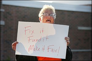 Shannon Conway, a TARTA worker, rallies outside TARTA headquarters. The slogan on her sign refers to TARTA’s funding system and the employees who are working under an expired contract.