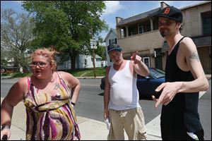 Heather Corum, left, with her brother Eric Camp, center, and Jeremy Loth, says the Toledo Police Department cameras installed in their East Toledo neighborhood haven’t made a positive difference. 
