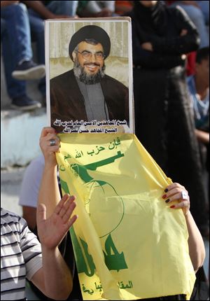 Syrian people from Julan and Palestinians hold a poster of the leader Hassan Nasrallah and the Hezbollah flag during a rally to support Syria in Balata refugees camp in the West Bank city of Nablus.