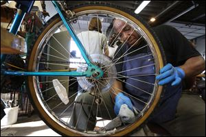Roy Lee Snow, of North Toledo cleans between the spokes of a bicycle he is helping to restore during a recent open bike night.