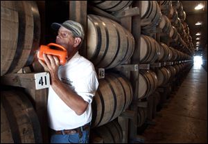 Dewayne Evans checks for leaks in the barrels of whiskey aging in a warehouse at the George Dickel Distillery near Tullahoma, Tenn. George Dickel is a subsidiary of liquor giant Diageo.